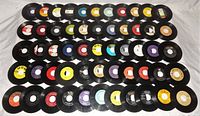 Photo showing all 55 loose vinyl 45 RPM records arranged in several rows on a white surface, various labels and colors visible