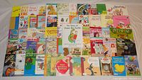 Image shows a large assortment of 56 children's books spread out on a surface with colorful covers depicting animals, trucks, dinosaurs, and characters. Books vary in size and style.