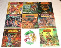 All eight Masters of the Universe He-Man Golden Books arranged in a 3x3 grid with the bottom middle position occupied by the He-Man & She-Ra DVD packaging, showing front covers and titles.
