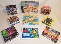 Photo of all nine jigsaw puzzle boxes laid out, showing diverse themes including Among Us, Dragonball, Looney Tunes, Pac Man, and others.