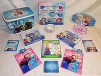 Photo showing the items laid out including Frozen themed storage bin and boxed dinnerware set, two diary sets, color & sticker set, gift bags, and media cases/discs.