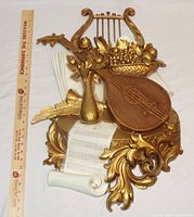 Photo of large vintage Syroco 1971 music themed wall hanging showing the front detail with lute, lyre, gold leaves, scroll with musical notes, and grape bunch.