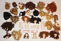 Photo showing porcelain doll heads, wigs, and limbs arranged flat on a white surface