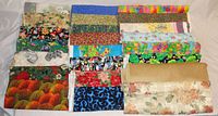 Multiple large fabric cloth pieces in various colorful and floral patterns folded on a flat surface