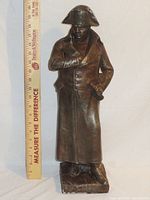 Full front view of the Napoleon Bonaparte statue with a ruler to show height (20 1/4 inches). Shows bronze finish and overall condition.
