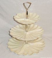 Front view of fully assembled 3-tier iridescent shell-shaped party serving tray with silver handle and metal post.