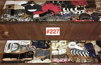 Two wooden drawers filled with an assortment of women's belts in a range of styles and colors.