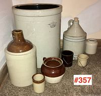 All eight stoneware jugs and crocks arranged on floor, showing various sizes and styles