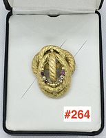 Brooch displayed in lined jewelry case showing overall shape, rope motif and pin closure
