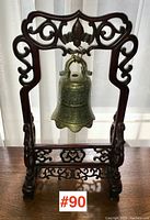 Front view of stand and bell centered on table against curtain backdrop