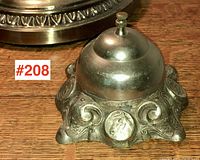 Front view showing embossed horse medallion and scrollwork on cast iron base with metal bell dome.
