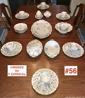 Full set arranged on wooden table showing 6 place settings with plates, cups, and saucers, large bowls, dessert bowls, vegetable servers, platters, gravy boat, and covered bowl.