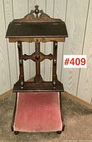Front view of oak prayer stand showing tilting top, carved crest and velvet kneeler.