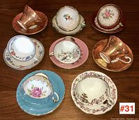 Eight teacup and saucer sets arranged in three rows on wood surface