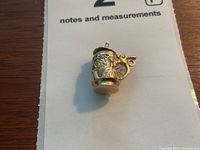 Front three-quarter view of charm showing handle and relief decoration on stein body