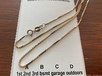 Full view of box link chain laid out on notes and measurements card