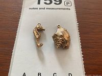 Conch shell and seahorse charms displayed on paper board