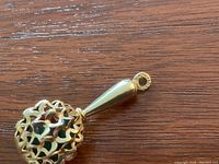 Side view of charm showing tapered handle and filigree sphere