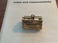 Front view of rectangular gold lobster trap charm with visible internal lobster