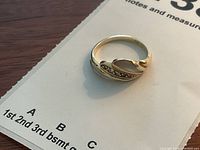 Top view of ring on paper backing showing 14k stamp inside band.