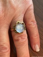 Ring worn on finger showing profile view of moonstone and scalloped bezel