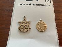 Front view of centennial star charm and round disc charm revealing design details