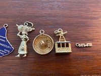 Front view of all five gold travel charms laid out