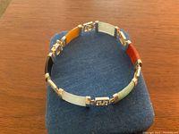 Full view of bracelet laid flat showing multicolor jade stones and silver character details