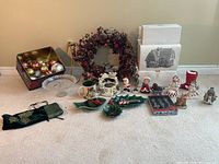 Wide view of all Christmas decorations displayed on the floor including the wreath, ornaments, figurines, stocking, candle, and other holiday decor pieces