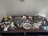 Overview of entire lot including trinket boxes, necklaces, watches, bracelets and rings arranged on table