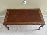 Top view of rectangular walnut coffee table with leather inset top showing scalloped edges and embossed border on leather.