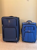 Photo showing both large Samboro and smaller Delsey suitcases side by side against a wall.