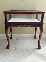 Front view of mahogany framed glass display case table showing Queen Anne legs and single drawer beneath display area.