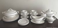 Full set of Royal Doulton china arranged on table showing all included pieces: tea pot, creamer, sugar bowl, gravy boat, cups and saucers, serving dish, salad and dinner plates