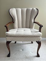 Front-facing view of upholstered occasional chair highlighting fan back and tufted seat