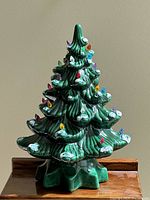 Front view of the vintage green ceramic Christmas tree showing colored bulb lights and snow accents on the branches.
