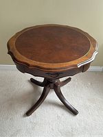 Top view showing the leather insert with gold tooling and the scalloped walnut edges of the table.