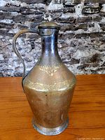 Full view of the antique brass vessel showing the body, handle, and patina.