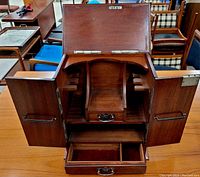 Front view open showing interior central compartment, side pipe holders and lower drawer