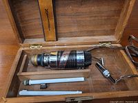 Overview of the shock treatment device and accessories in wooden box, showing main unit with adjustable dial and two rod attachments plus brush.