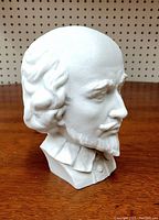 Side angled view of white bisque porcelain bust showing detailed facial features and hair texture.