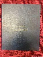 Black presentation binder cover with gold embossed 'Norman Rockwell' lettering.