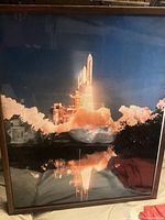 Close-up of one framed photo showing the Discovery Space Shuttle at liftoff with plume and water reflection