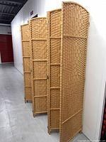 Room divider with 8 rattan woven panels connected by brass hinges, shown folded slightly angled from side.