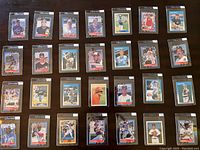Photo showing 30 baseball cards arranged in rows, each card in protective sleeve, featuring various 1988 Fleer, Topps, and Donruss baseball players in mint condition.