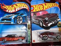 Close up of red diecast car with flame decals and maroon Classic Nomad car in blister pack packaging.