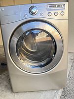 Front view of silver LG electric clothes dryer showing the large circular door and LG badge.