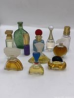 Photo showing ten miniature perfume bottles in various shapes and colors, arranged on a white surface.
