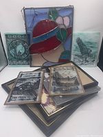 Overall view of stained glass pieces and framed artwork showing large stained glass panel with woman's profile and four smaller stained glass pieces depicting San Francisco landmarks and other motifs