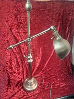 Full view of the adjustable brushed silver/bronze table lamp showing base, pole, arm and shade.